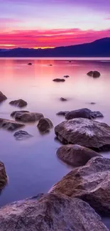 Serene sunset over lake with rocks and purple sky.