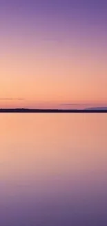 Serene sunset over a calm purple lake with an orange sky.