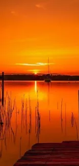 Serene sunrise over calm orange waters with silhouetted boat and dock.