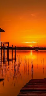 Vibrant orange sunset over a serene lake with reflections.