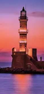 Lighthouse silhouette against a colorful sunset sky over a tranquil ocean.