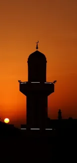 Silhouette of a mosque at sunset with an orange sky backdrop.