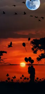 Silhouette at sunset with balloons and birds against an orange sky over a lake.