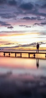 Silhouette on a pier with a vibrant sunset sky.