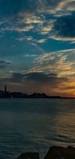 Sunset over calm waters with distant city silhouette and colorful sky.