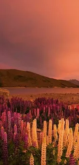 Serene sunset over a mountain lake with vibrant flowers in the foreground.