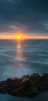 Stunning sunset over a calm ocean with rocky coast.