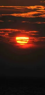 Vivid orange sunset with ocean silhouette and clouds.