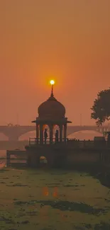 Elegant temple silhouette at sunset over serene river.