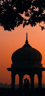 Silhouette of pavilion against orange sunset sky.