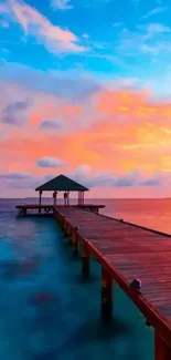 Serene sunset over a wooden pier extending into the vibrant ocean.