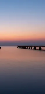 Serene sunset over a pier with calming blue and orange hues.