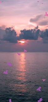 Sunset view over a calm ocean with birds in a pastel sky.