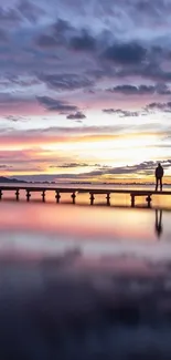 Silhouette on a pier at sunset over calm water.