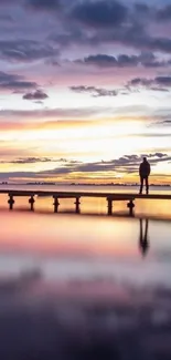 Peaceful sunset over water with vibrant reflections and silhouette on a pier.