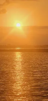 Tranquil sunset over calm water with orange and golden hues.