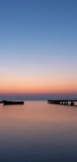 Serene sunset over water with boats and pier silhouetted against colorful sky.