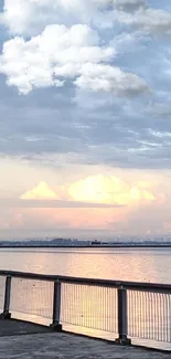 Serene sunset over a tranquil waterfront with calm waters and soft clouds.