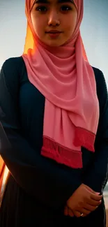 Serene portrait of a woman in a hijab at sunset on the beach, with warm orange hues.