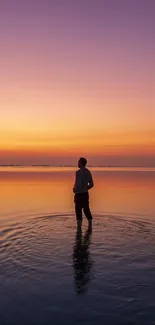 Purple sunset over calm water with lone figure reflecting in the scene.