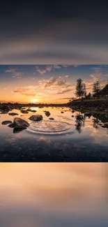 Serene sunset reflecting on calm water with colorful sky and rocky shoreline.