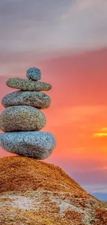 Stacked stones with a vibrant sunset in the background creating a serene scene.