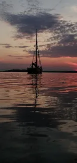 Serene sailboat at sunset on calm waters reflecting the vibrant evening sky.