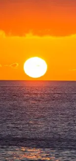 Tranquil sunset over ocean with sailboat silhouetted.