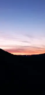 Serene silhouette sunset over mountains with vibrant colors.