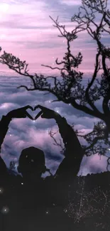 Silhouette forming heart against sunset sky and clouds.