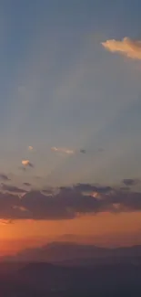 Serene sunset with clouds and mountains in the horizon.