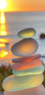 Stacked stones with a vibrant sunset over the ocean, creating a serene mobile wallpaper.