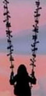 Silhouette of a person on a swing with a pastel sunset sky background.