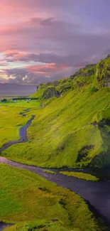 Serene green valley at sunset with colorful sky.