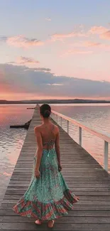 Woman in a dress on a wooden walkway at sunset.