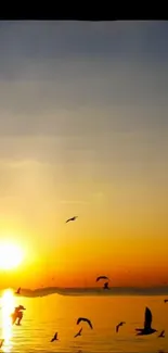 Serene sunset over water with birds flying, vibrant orange sky.