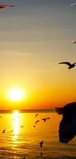 Vibrant sunset over ocean with birds flying.