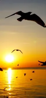 Serene sunset with birds flying over ocean at golden hour.