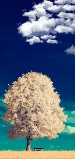 Serene tree standing alone under a deep blue sky with fluffy clouds.