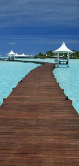 Wooden pier extending into turquoise tropical waters under a blue sky.