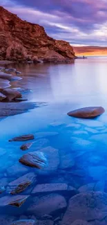 Serene twilight lake view with rocky shores and vivid sky.