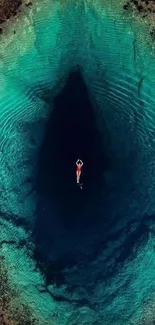 A lone swimmer in turquoise waters, viewed from above.