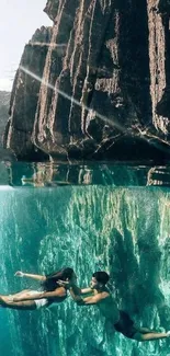 Divers explore underwater cliff in serene backdrop.