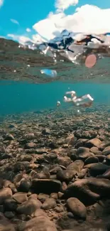 Underwater view stones in clear water with blue sky.