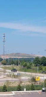 A serene view of a highway under a clear blue sky with surrounding greenery.