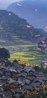 Serene village in lush hills at dusk with glowing lights.