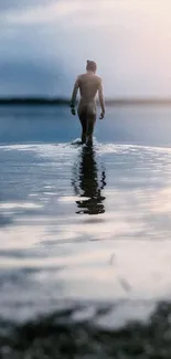 A lone figure stands in calm water, reflecting the serene landscape.