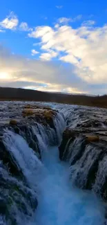 Waterfall cascading under a blue sky, capturing serene nature.