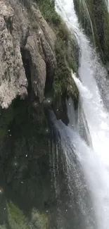 Cascading waterfall over rocky cliffs with lush greenery.