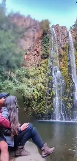 Couple by a serene waterfall amidst lush greenery.